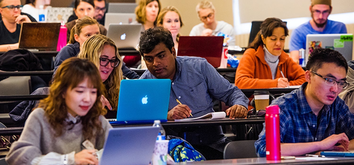 Graduate students working on laptops in classroom